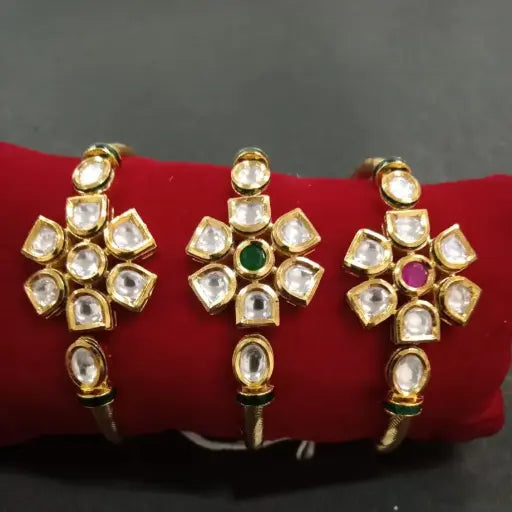 AIVY LUXE geometric kundan bangles with white stones and green and pink center accents on red cushion