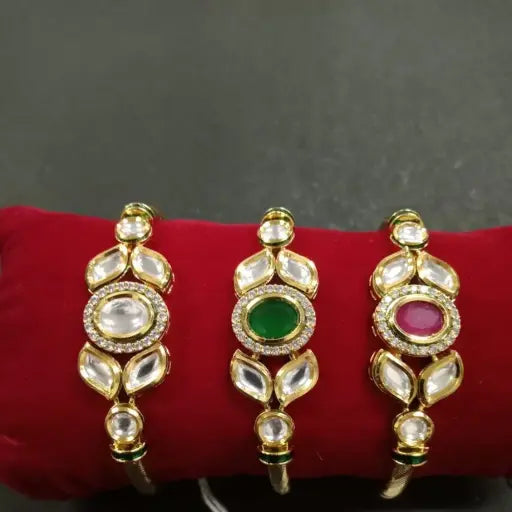 AIVY LUXE kundan gold bangles with white stones and green and pink center gems on red cushion