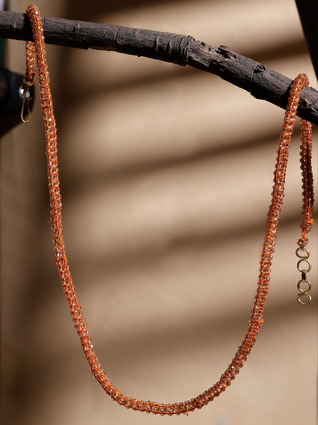 AIVY LUXE orange beaded necklace for women hanging on a dark wooden branch with a beige background