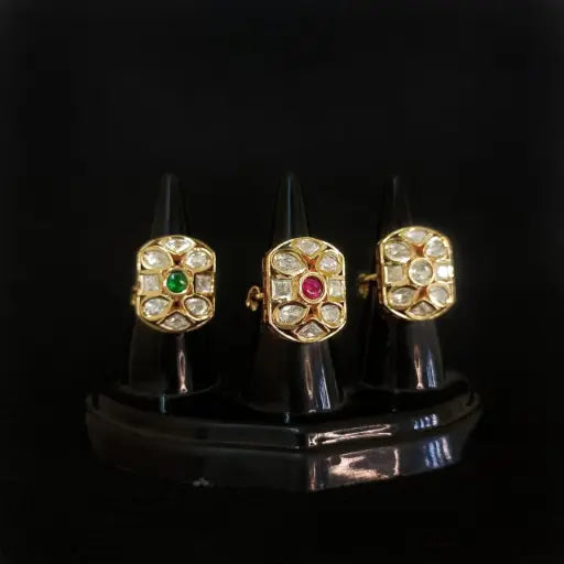 Square-shaped kundan rings with green, red, and white stones in a gold base