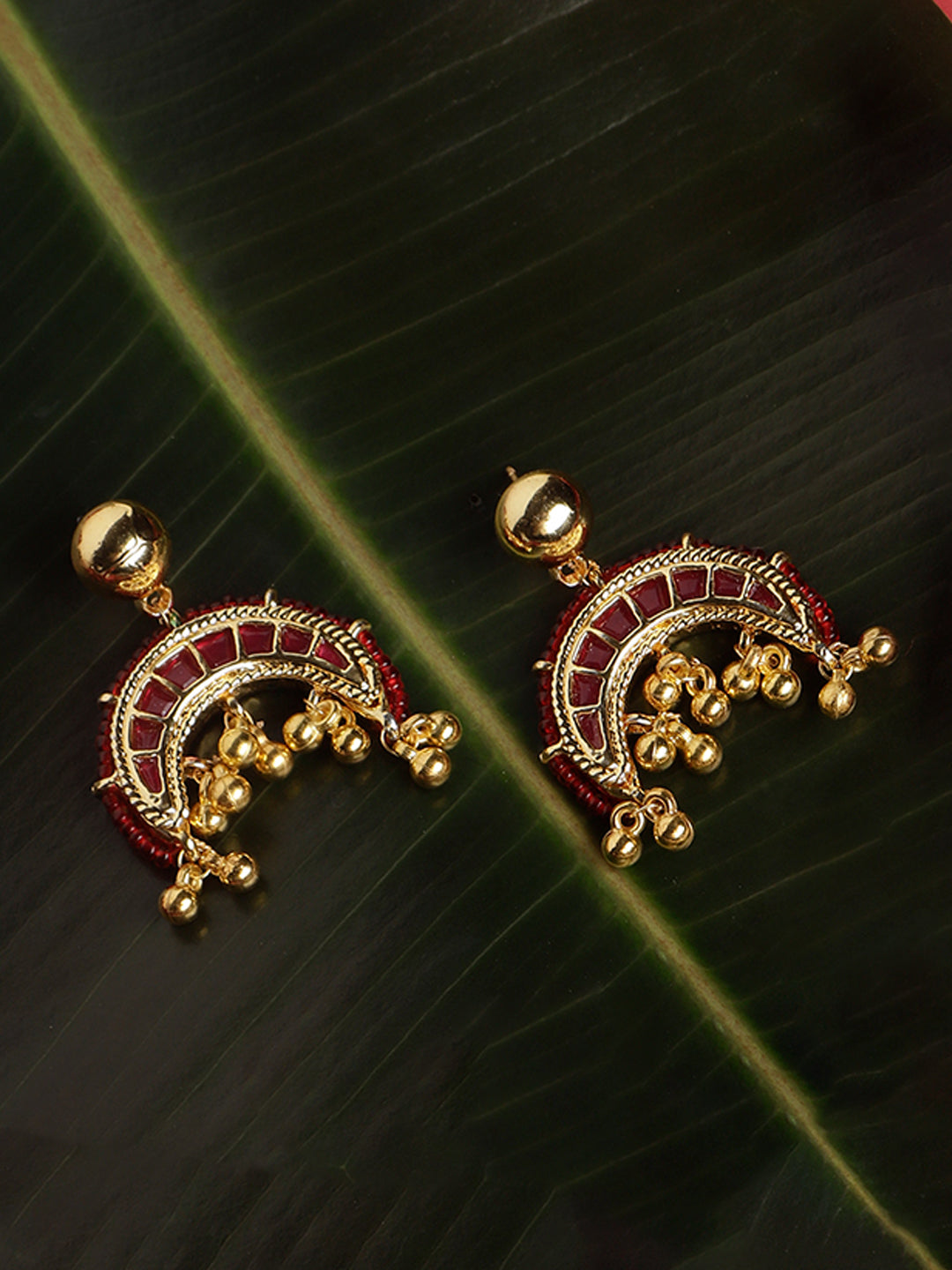 AIVY LUXE red and gold statement earrings with intricate bead and bell detailing on dark green leaf background
