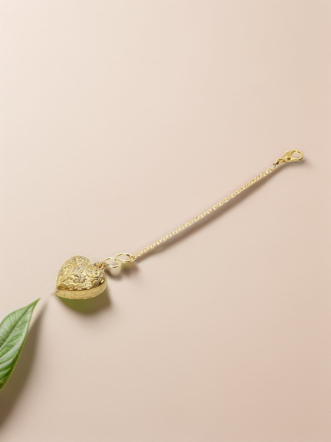 AIVY LUXE gold heart watch charm with intricate floral design and chain clasp on beige background