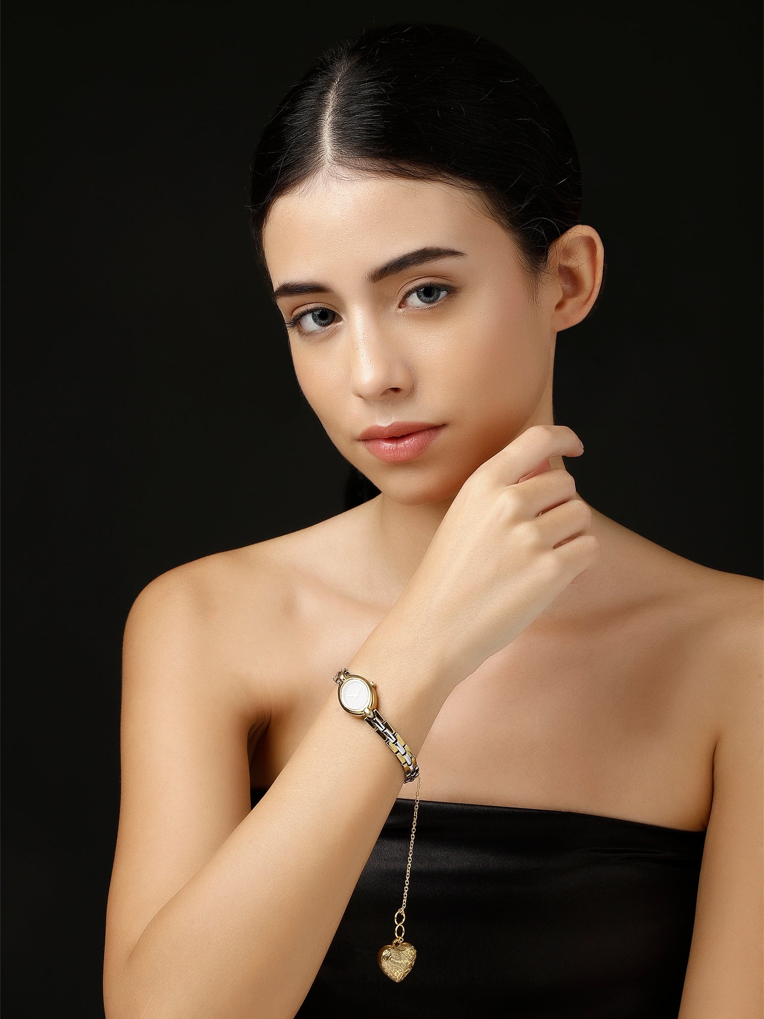 AIVY LUXE gold heart watch charm dangling from a silver bracelet on a woman’s wrist