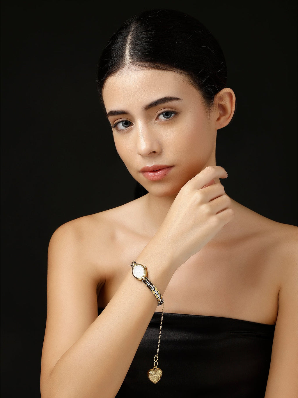 AIVY LUXE gold heart watch charm dangling from a silver bracelet on a woman’s wrist