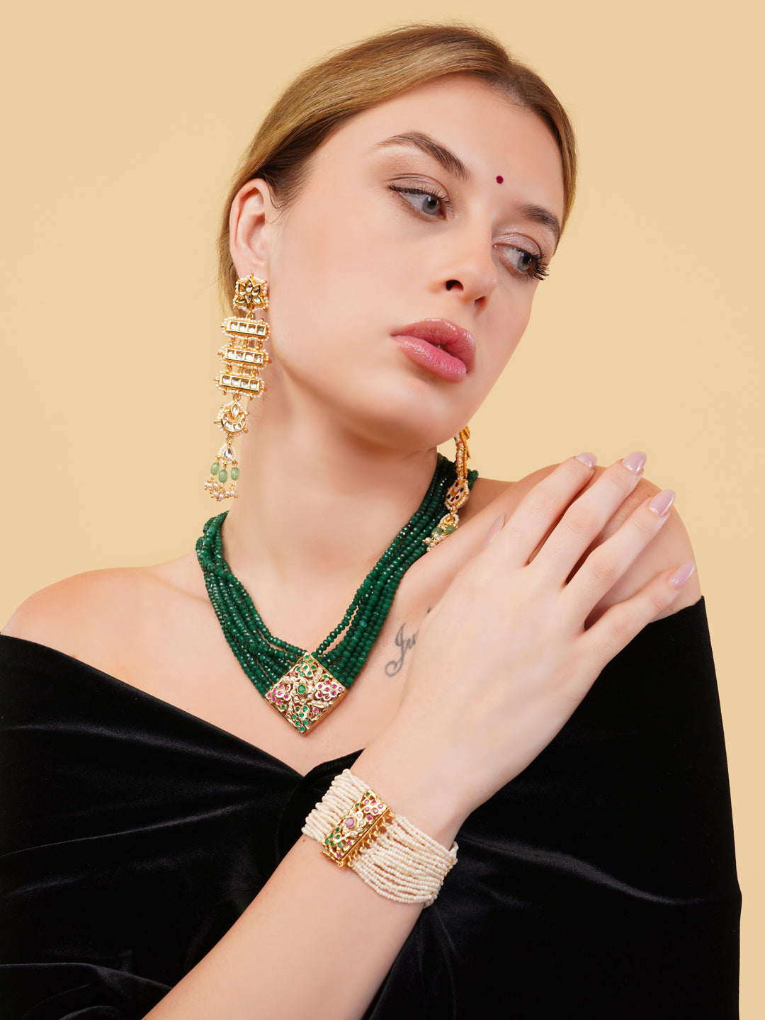 AIVY LUXE green beaded necklace with gold pendant worn by woman in black off-shoulder dress