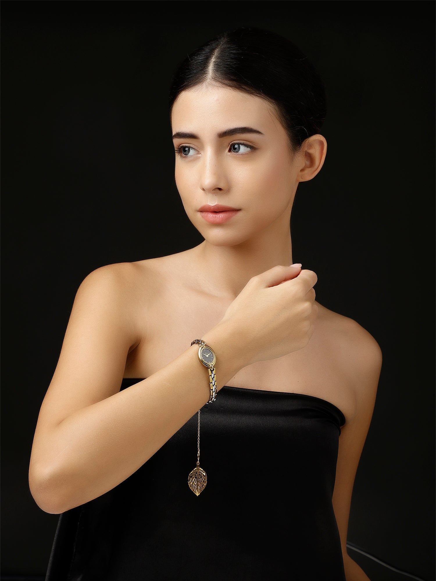 Woman wearing AIVY LUXE handcrafted watch charm for women with leaf pendant on chain bracelet