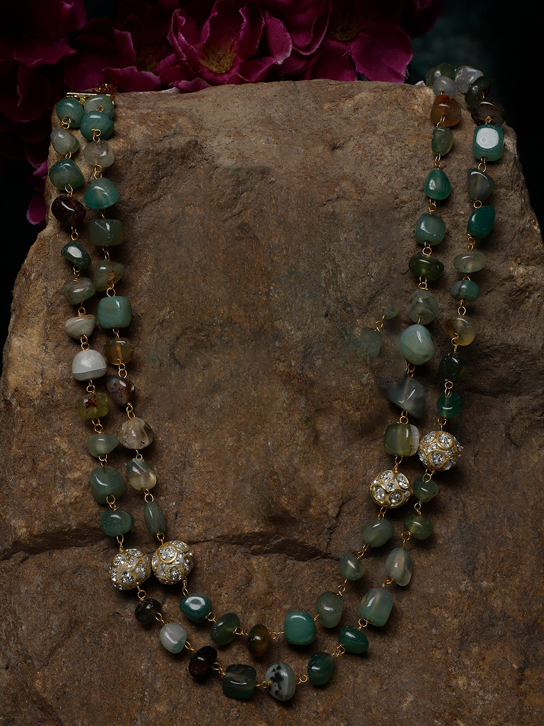 AIVY LUXE layered green gemstone necklace with gold accents and intricate bead detailing on a stone background