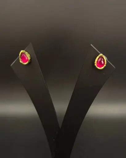 AIVY LUXE minimal gold stud earrings with red teardrop gemstones on black display stand