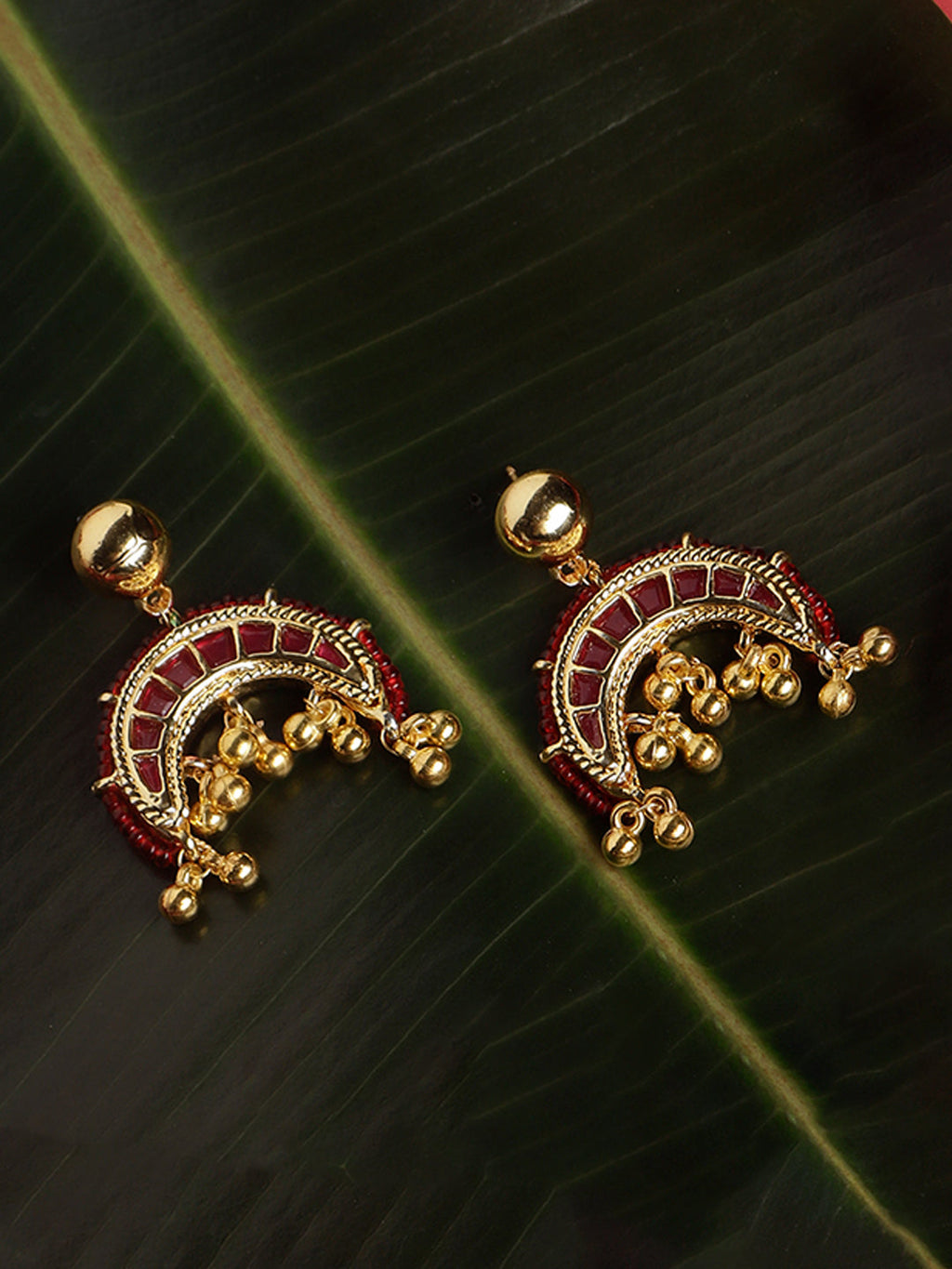 AIVY LUXE red and gold statement earrings with intricate detailing and dangling gold beads on dark green leaf