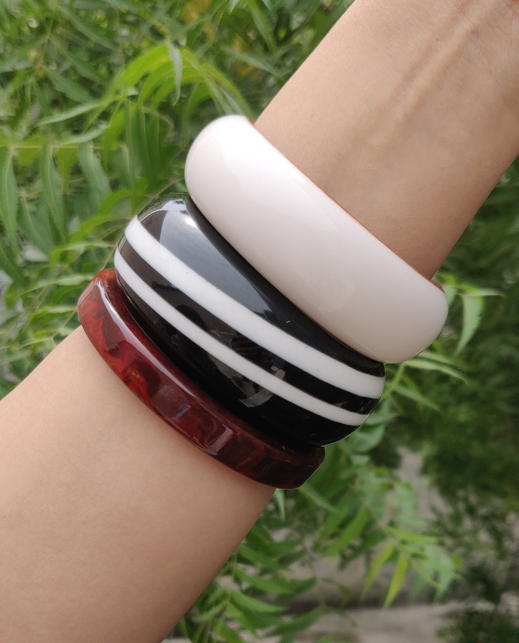 AIVY LUXE red and white resin bracelet set shown on a wrist with greenery background