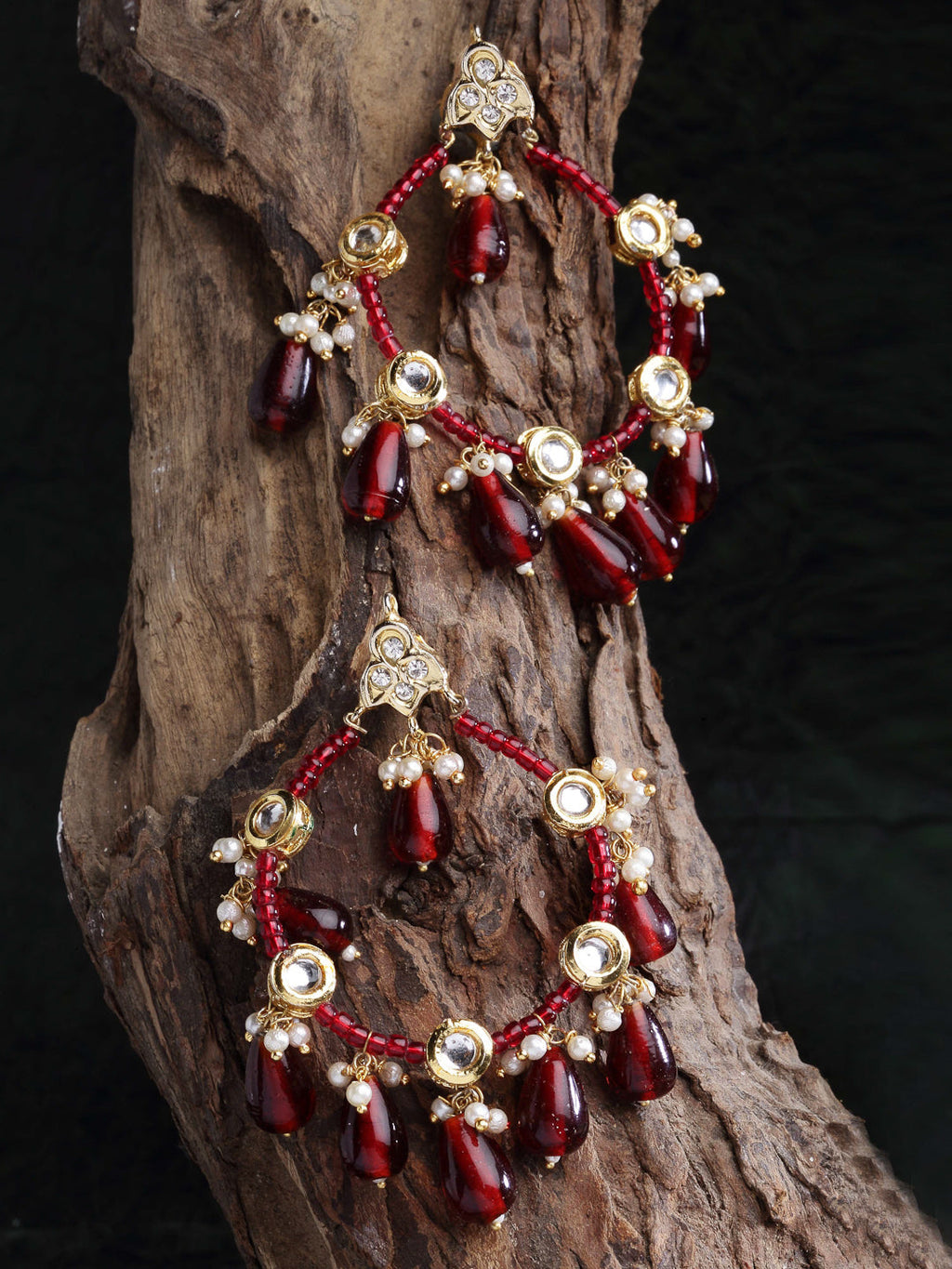 AIVY LUXE red stone statement earrings with gold land pearl accents hanging on rustic wood