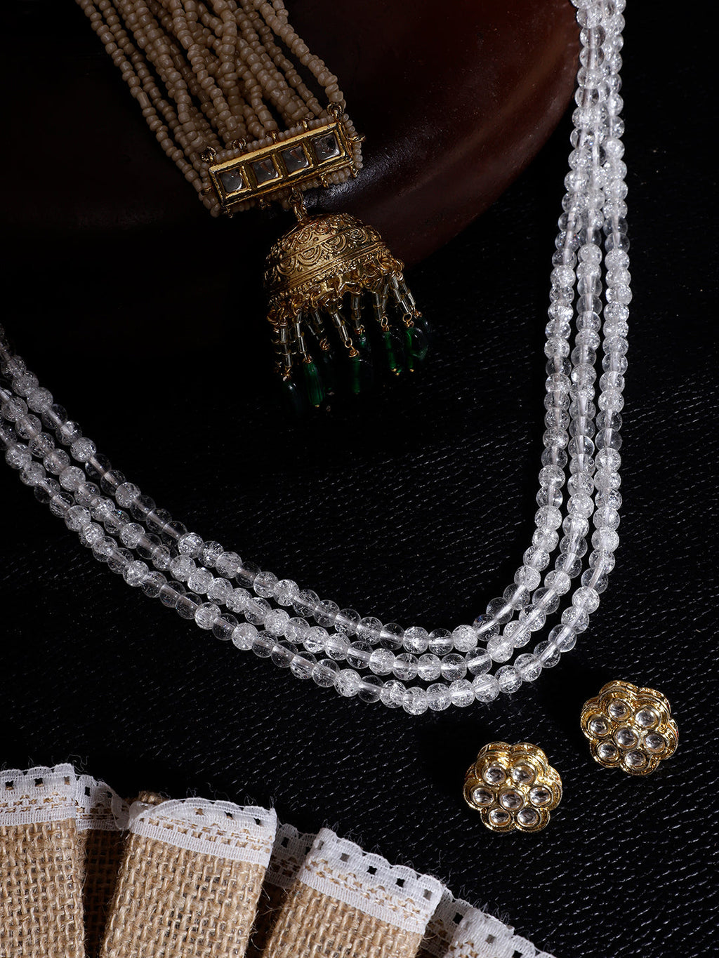 AIVY LUXE traditional green dangle earrings with intricate gold design displayed with pearl necklace and fabric