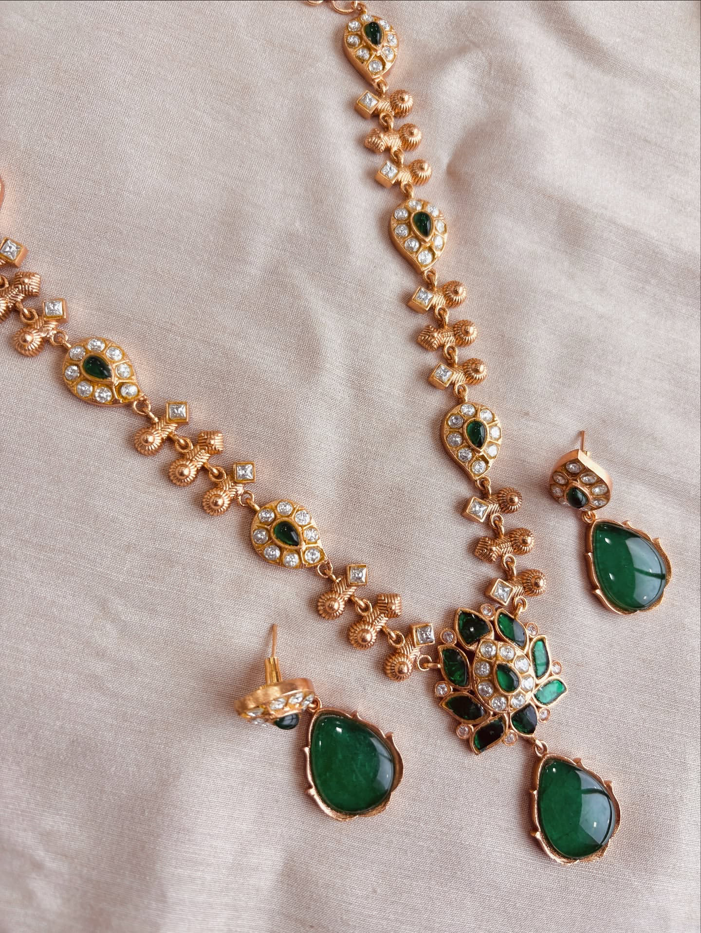 AIVY LUXE traditional green stone necklace set with gold detailing and matching earrings on beige fabric
