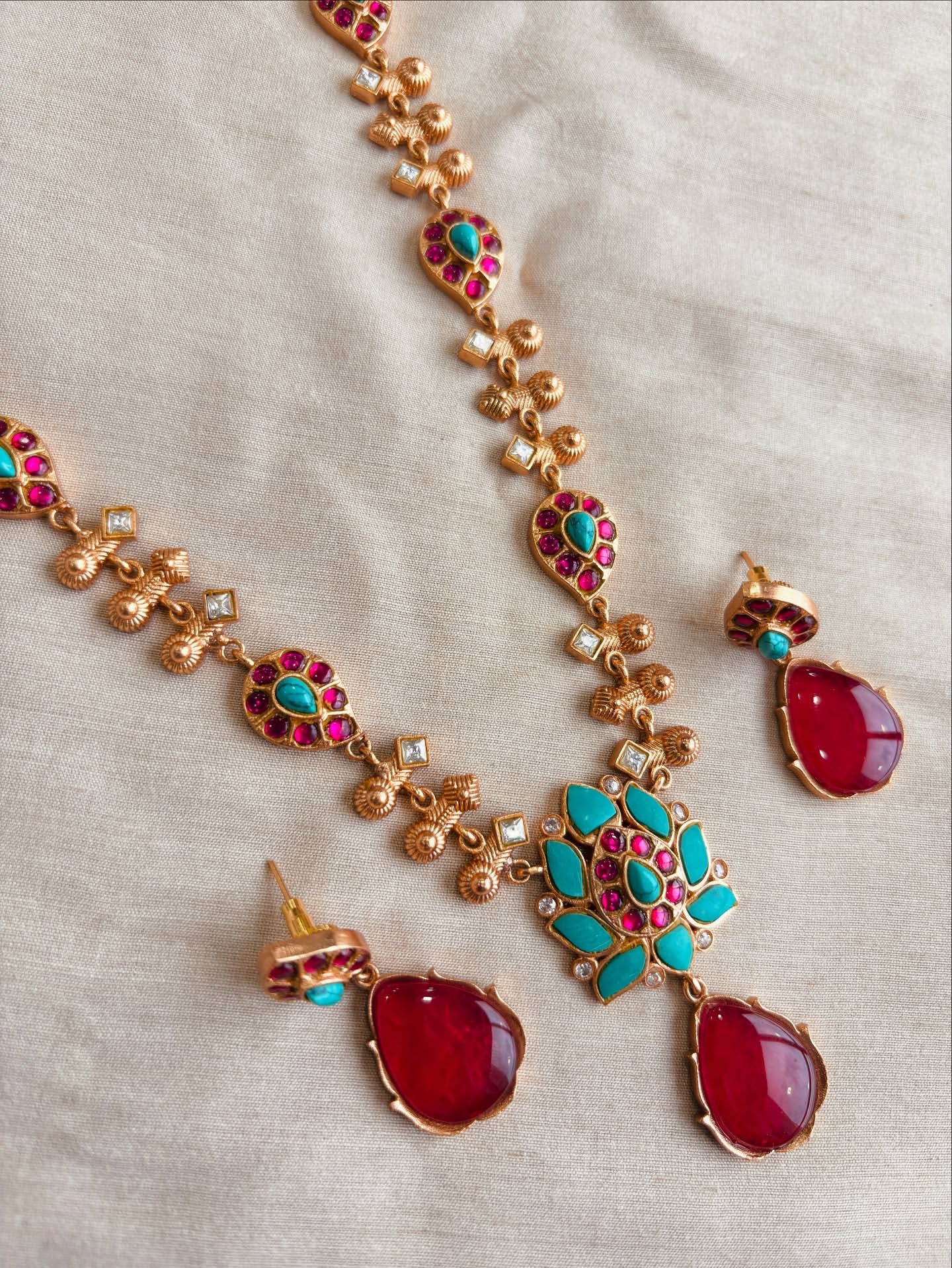 AIVY LUXE traditional green stone necklace set with red and green stones and gold detailing on beige background