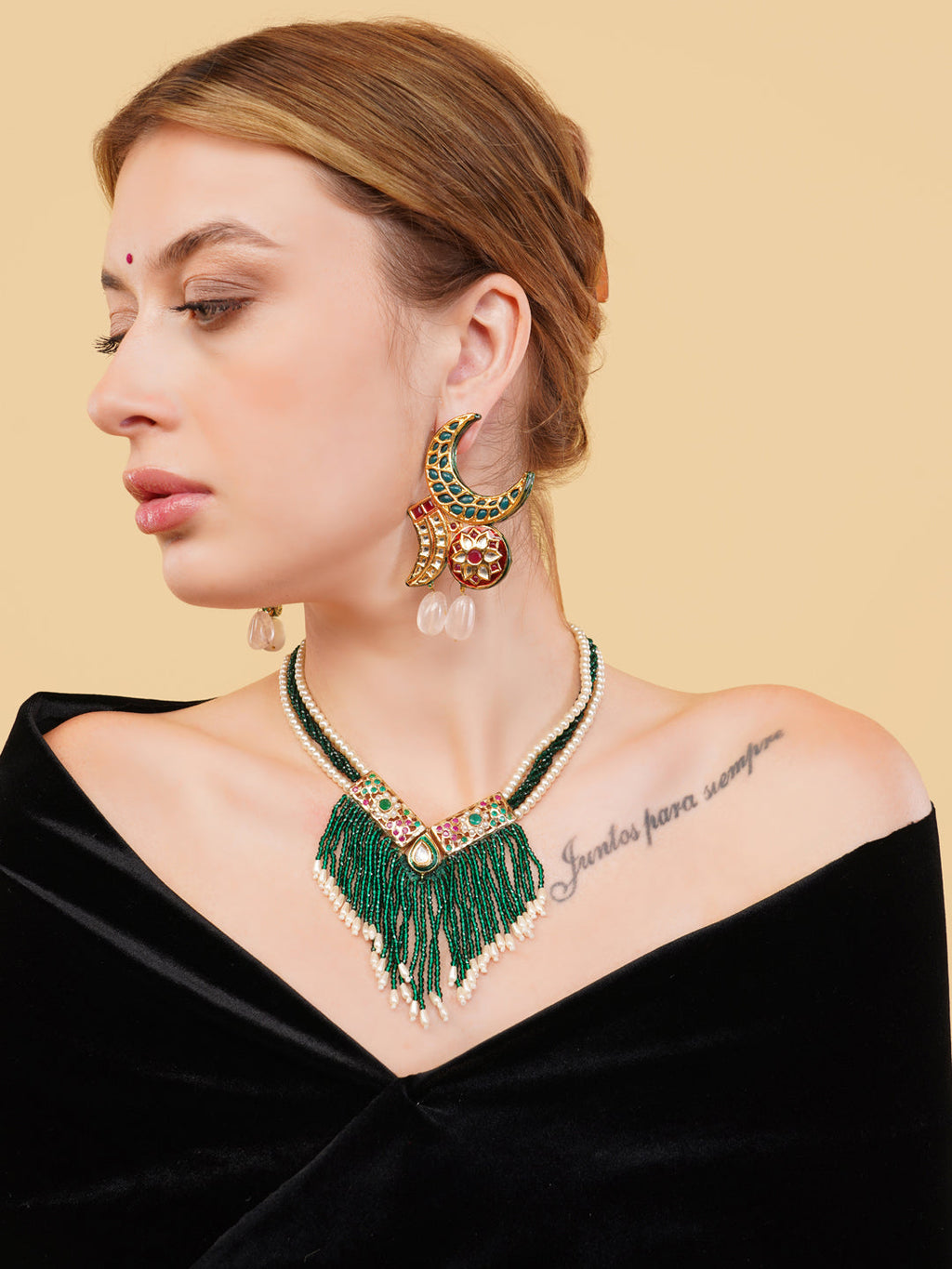 Emerald pearl stone Indian drop earrings worn by woman with matching green necklace and black top